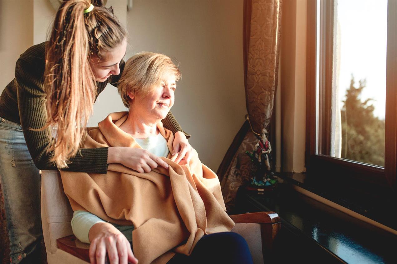 younger woman wrapping older woman in blanket