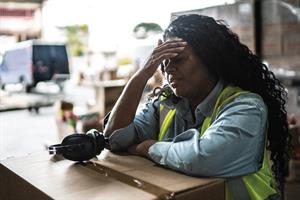 Woman sat by a box with her hand on her forehead