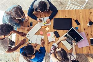 Overhead view of young business people around wooden desk