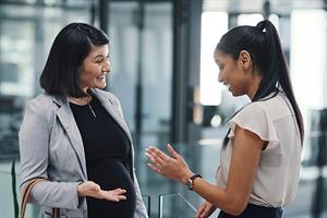 pregnant woman at work speaking with a colleague