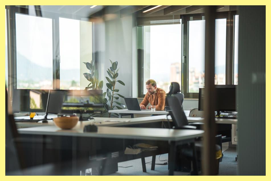 Person sitting at a laptop in an empty office