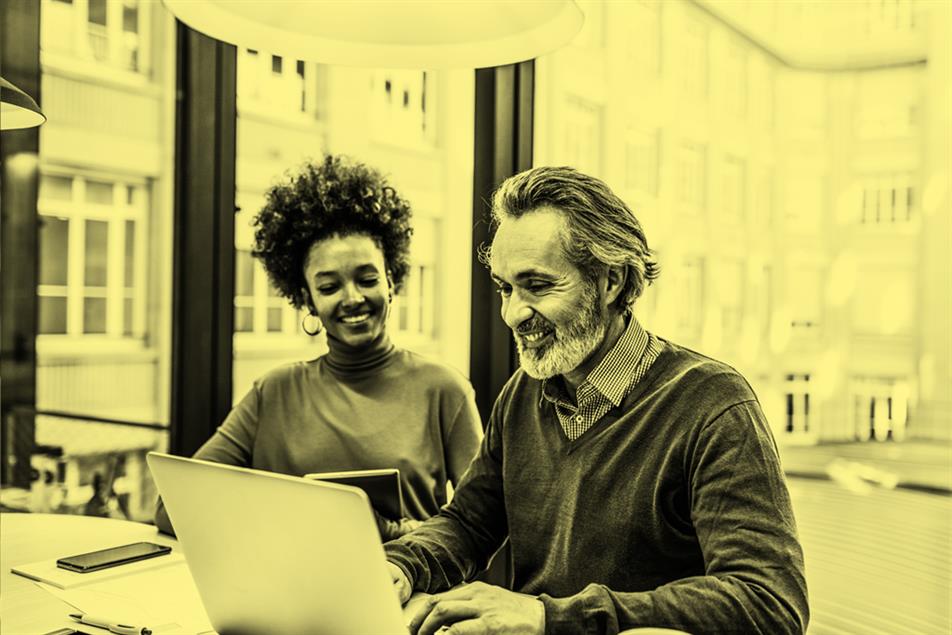 Two people sat in front of a laptop