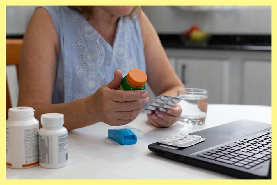 A woman sitting at a desk with lots of medication by laptop