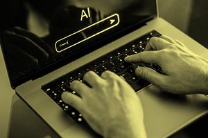 Close up of hands typing on a laptop with AI on the screen