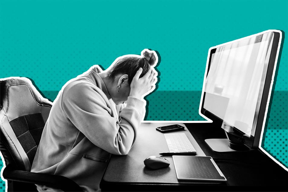 Person sat in front of a computer screen with head in their hands