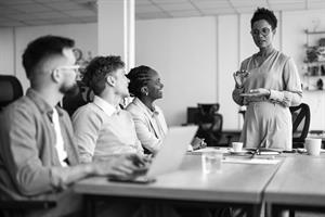 Person stood talking to a group of people sat listening