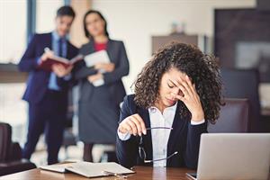 Woman at laptop with hand on here face
