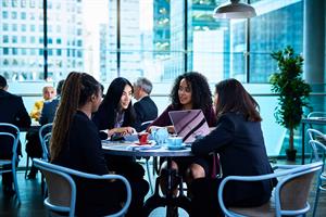Women sat around table with laptop and coffee cups