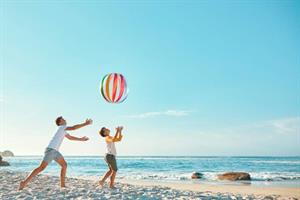 People on beach with beach ball in air