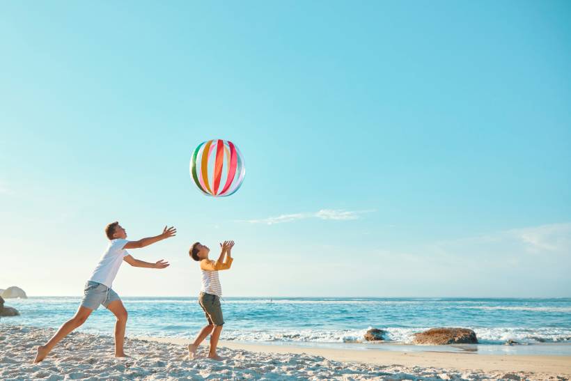 People on beach with beach ball in air