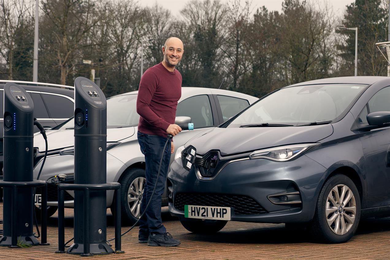Smiling man at electric car charging point