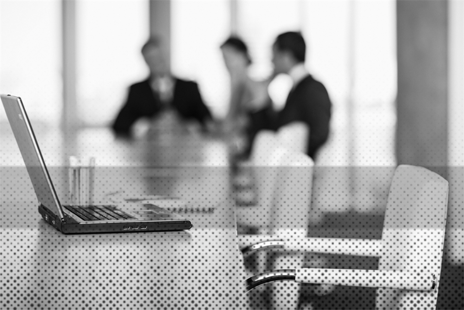 Empty seat in front of a laptop with people sitting in the background