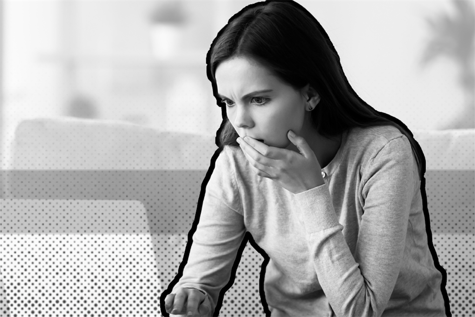 Person with hand over their mouth in front of a laptop