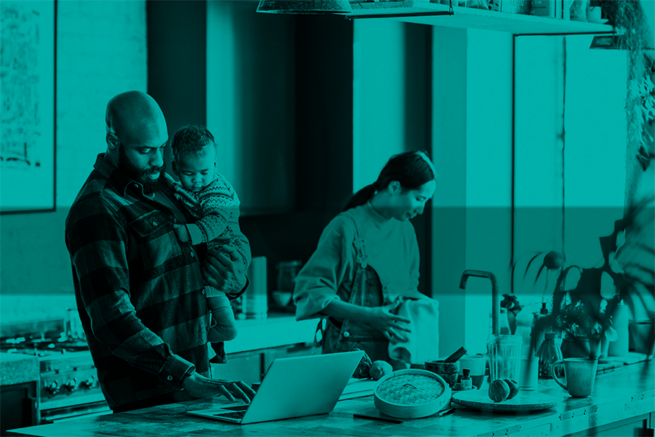 Man holding child while typing on laptop