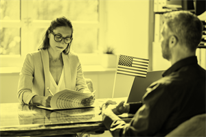 Two people sat at a desk with a US flag