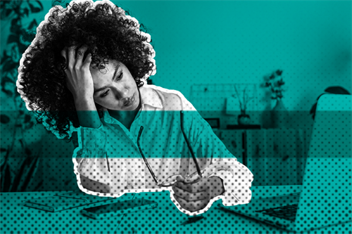 Person sat in front of a laptop with hand on their head