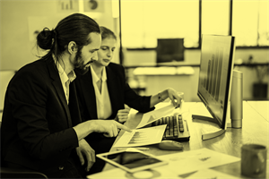Two people sat at a desk looking at documents