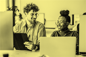Two people sat smiling in front of computer screens