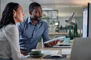 Two people sat at a desk looking at a computer