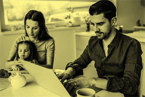 Person sat at a laptop with another person and a child