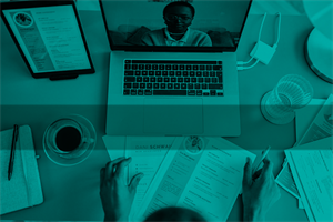 Close of someone sat at a laptop with papers