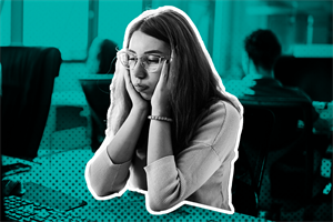 Person sat at a desk in an office with face leaning on their hands