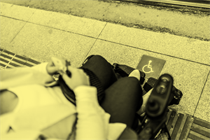 person in a wheelchair waiting in an accessible area for public transport