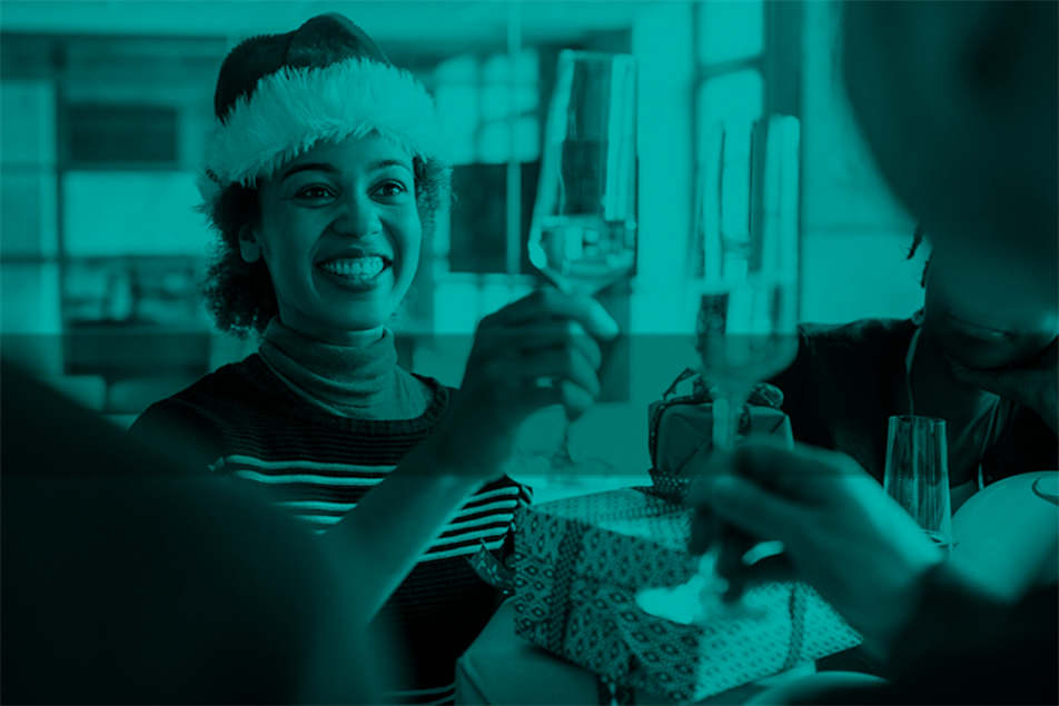 Person in a Santa hat and holding up a glass