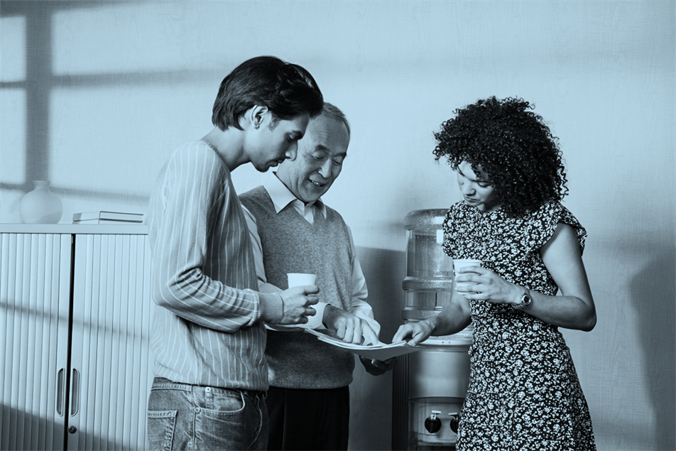 Group of people standing by a water cooler looking at papers